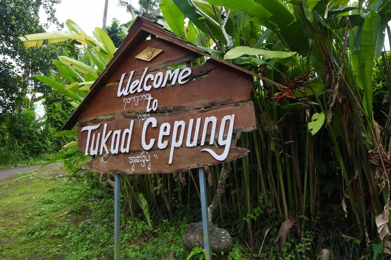 large dark wooden sign with white words that say "welcome to tukad cepung"