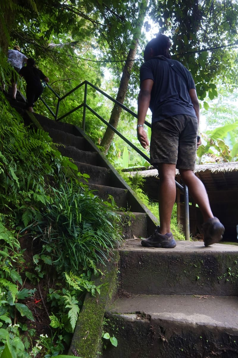 black traveler walking up semi-steep stairs heading up to tukad cepung waterfall